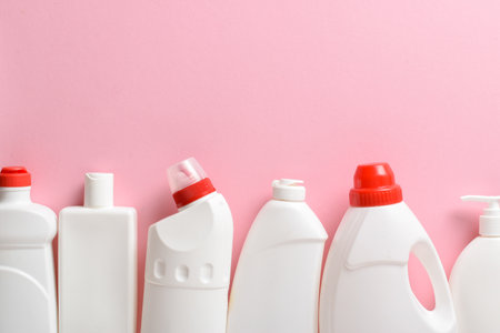 Plastic white bottles lie on a light pink background. Layout of bottles with household chemicals for cleaning and disinfection of the room. copyspace. Flat lay, top view.の写真素材
