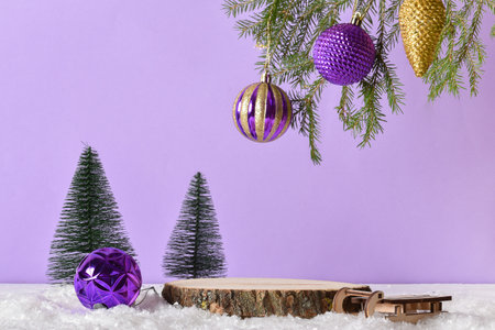Wooden podium in the snow with festive decor on a light purple background. Christmas decoration with...