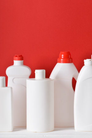 Plastic bottles on a red background. Layout of bottles with household chemicals for cleaning and disinfection of the room. copy spaceの写真素材