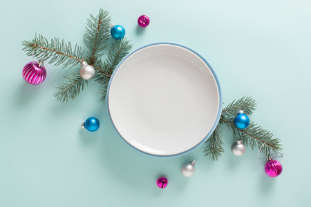Christmas table setting and festive decor on a light blue background with fir branches and glass...