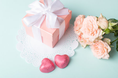 A gift with a bouquet of flowers and a knitted heart on a light blue background. An invitation for Valentine's Day. Space for copying. Flat position, top view.の写真素材