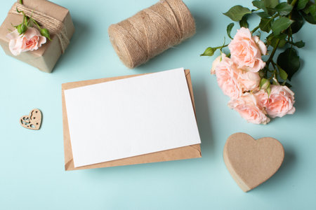 Close-up of a kraft envelope on the background of a gift and a bouquet of bush roses. Layout of an invitation to a wedding, birthday, anniversary, romantic date. copyspace. Flat lay, top view.の写真素材