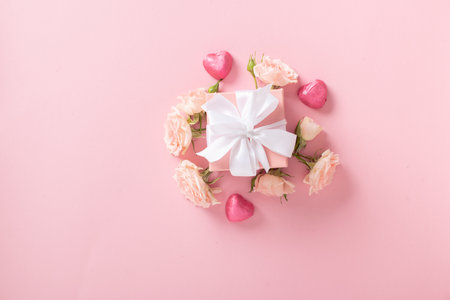 Valentines Day background. A banner layout with a gift, roses and hearts on a light pink background with a space for text.の写真素材