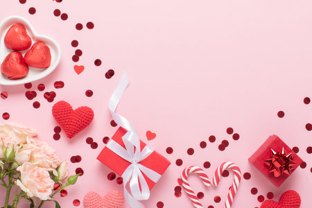 A mock-up of a Valentine's Day banner with gift boxes, knitted hearts and a bouquet of roses on a pink background. Valentine's Day greeting card template. Space for copying. Flat position, top view.の写真素材