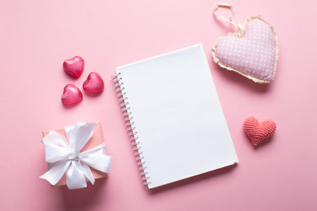 An open notebook with a gift and sweets on a light pink background. Valentine's day. Space for copying. Flat position, top view.の写真素材