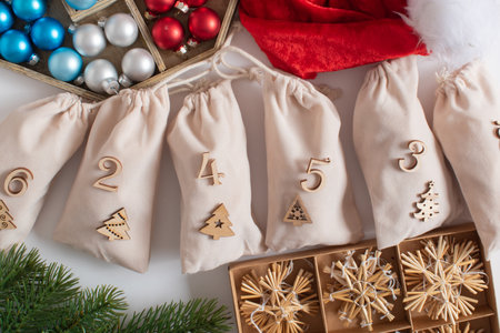 Christmas advent calendar with gift velvet bags and wooden numbers on a white background. Eco-friendlyの写真素材