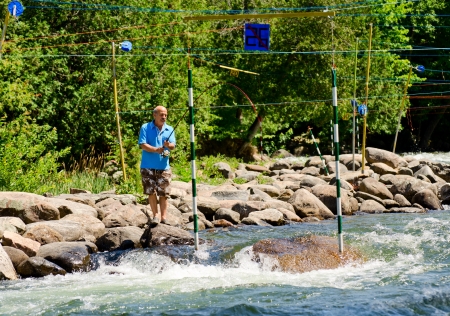 MINDEN, ONTARIO - JULY 21  An unidentified fisherman casts his line between the slalom gates at Ontario Summer Race 2012 on July 21, 2012 at Gull River in Minden, Ontario, Canada のeditorial素材
