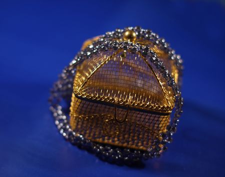 Close up of the box made of golden colored wire. Blue background.の写真素材