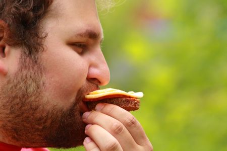 Young man eating the cheese sandwich