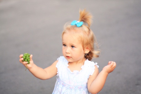 Portrait of the little pretty girl holding grapesの写真素材