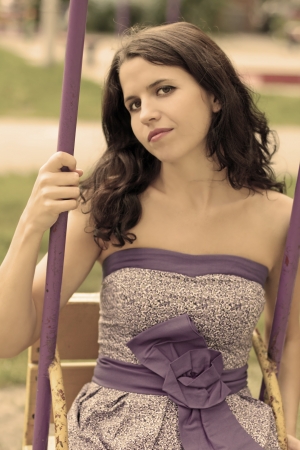 Portrait of the young beautiful lady sitting on the swingの写真素材