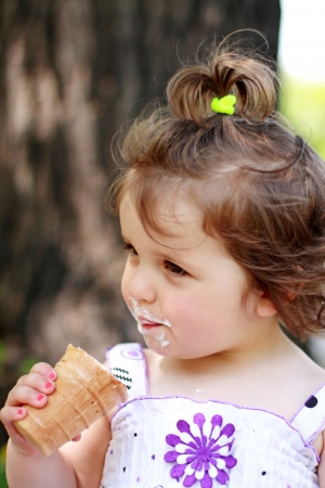 Outdoors portrait of the lovely little girl with ice-creamの写真素材