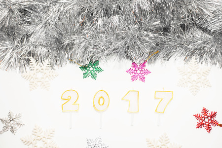 Christmas or New Year decoration candles "2017", colorful hanging and silver christmas tinsel on white wooden background.の写真素材