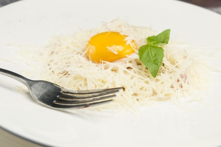spaghetti with cheese and egg on a white plate in a restaurantの写真素材