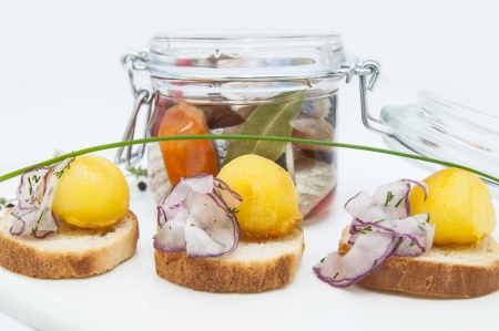pickled herring in a glass jar with potato canapesの写真素材