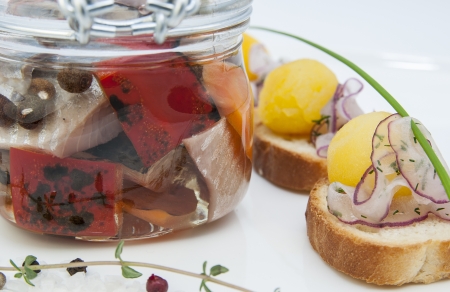 herring in a glass jar with potato canapesの写真素材