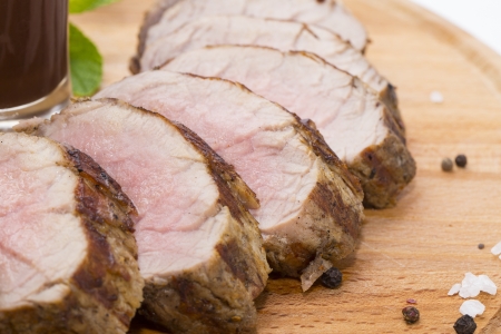 meat roasted on a grill with vegetables on a wooden plateの写真素材