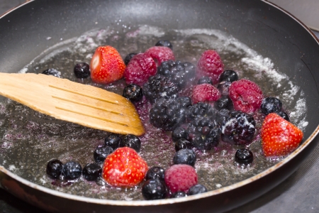 cooking berries in a pan in the kitchen at the restaurantの写真素材