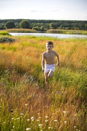 boy running on the field in summerの写真素材