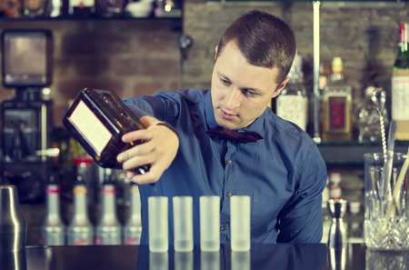 young man working as a bartender in a nightclub bar