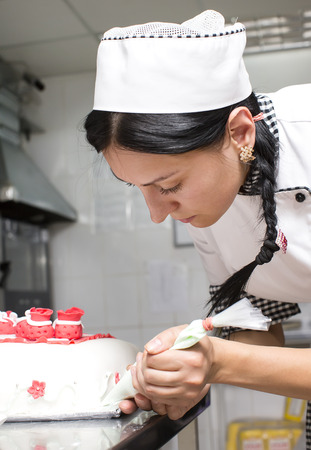 pastry chef decorates a cake in a candy storeの写真素材
