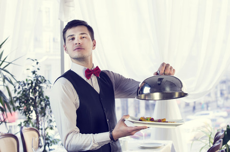 waiter with a tray of food in the restaurant hallの写真素材