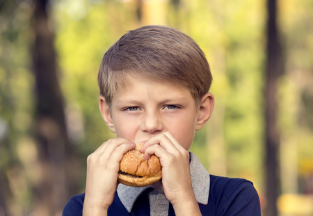 boy outdoors eating a hamburgerの写真素材