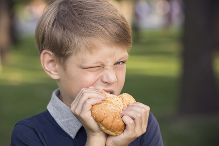 boy outdoors eating a hamburgerの写真素材