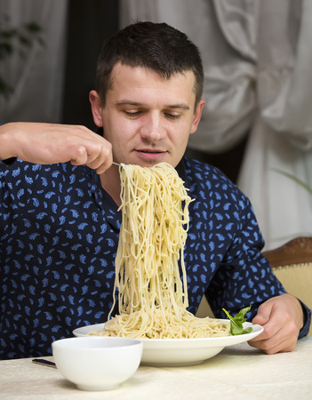 man eating a large portion of pasta in a restaurantの写真素材