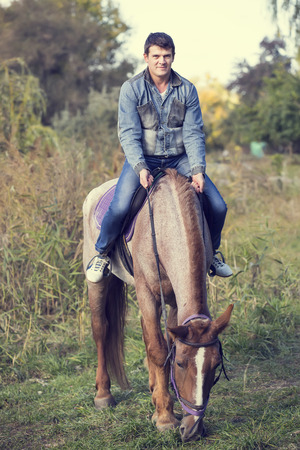 horse ride young guy autumn forestの写真素材
