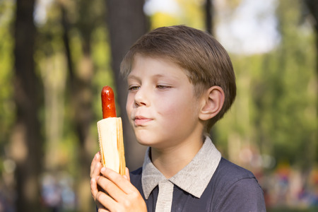 boy eating a hot dog on the streetの写真素材
