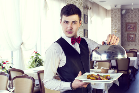 waiter with a tray of food in the restaurant hallの写真素材
