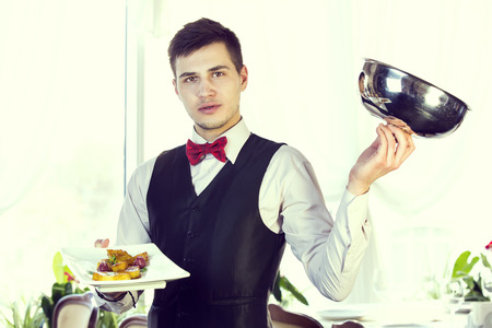 waiter with a tray of food in the restaurant hallの写真素材