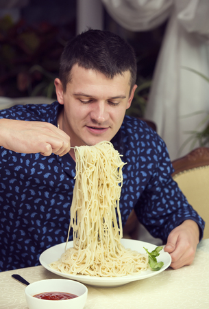 man eating a large portion of pasta in a restaurantの写真素材