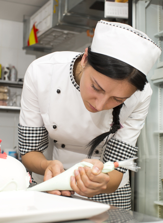 pastry chef decorates a cake in a candy storeの写真素材
