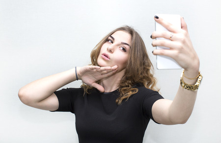 Girl doing self phone on a white backgroundの写真素材