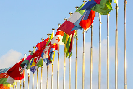 different countries flags on flagpoles on the sky background