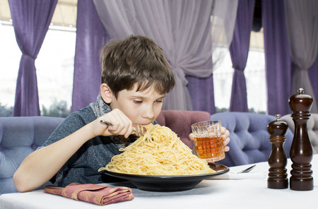 The boy is appetizing eats a large Italian spaghettiの写真素材