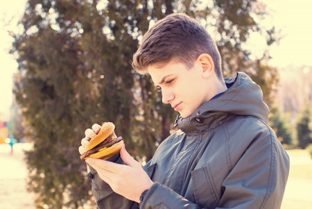emotional young guy eating a cheeseburger on the natureの写真素材