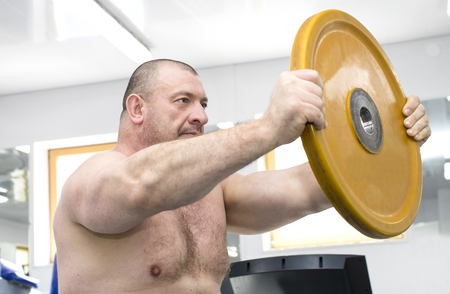 The adult brutal man is engaged in power bodybuilding in the gymの写真素材