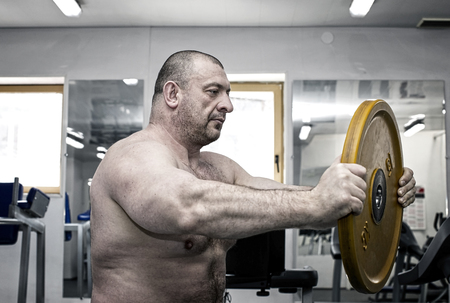 The adult brutal man is engaged in power bodybuilding in the gymの写真素材