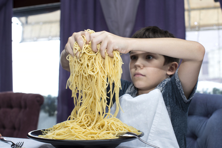 The boy is appetizing eats a large Italian spaghettiの写真素材