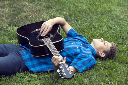 Young sad guy with an acoustic guitarの写真素材