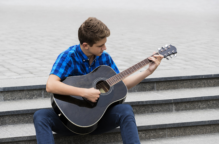 Young sad guy with an acoustic guitarの写真素材