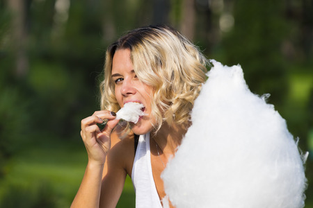 Girl eating sweet cotton candy in a summer parkの写真素材