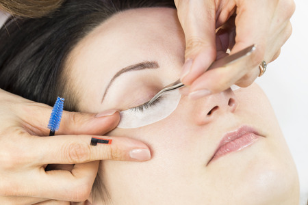 The process of eyelash extension to a woman in a beauty salon