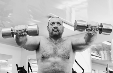 The adult brutal man is engaged in power bodybuilding in the gymの写真素材