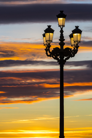 Lighted lanterns against the backdrop of the setting sun on the streets of Madridの写真素材