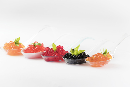 Plastic spoons with fish caviar on a white background.の写真素材