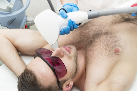 A young man on a procedure of laser hair removal in the salon of aesthetic beauty.の写真素材
